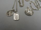 plusieurs colliers et pendentifs en argent posés sur une table