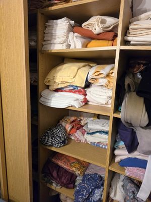 a closet filled with lots of folded clothes and folded towels