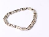 gros plan d'un bracelet en chaîne en argent sur une surface blanche
