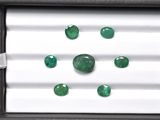 three emeralds in a box on a white surface