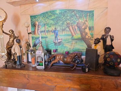 un tableau accroché au mur au-dessus d'une cheminée sur laquelle se trouvent des statues et une horloge