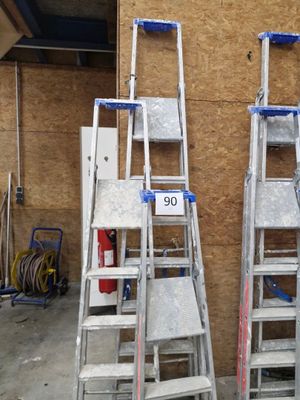 Plusieurs échelles sont alignées contre un mur dans un garage