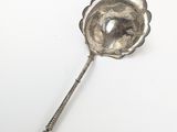 une cuillère en argent ornée d'une fleur sur une surface blanche