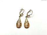 pair of gold tone earrings with mother and child ' s face on them