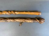pair of carved wooden walking canes sitting on top of a blue surface