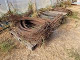 un tas de fil barbelé posé par terre près d'une clôture