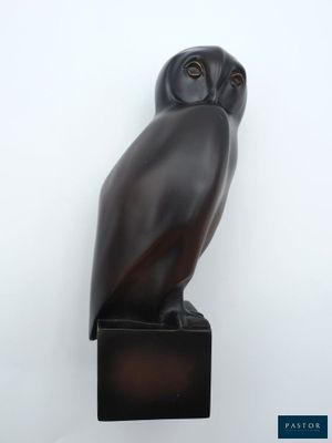 une statue de chouette noire posée sur un bloc de bois
