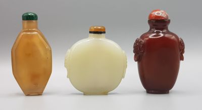 trois flacons à tabac en verre posés les uns à côté des autres sur une surface blanche