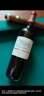 une bouteille de vin posée sur une table de billard, à côté d'une queue de billard