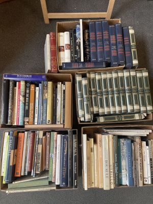 several boxes of books are stacked on the floor in front of a chair