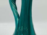 a green vase with a design on it on a white surface