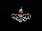 a close up of a pendant with a red stone in it