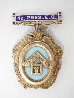 une médaille dorée et bleue sur laquelle figure une maison, entourée d'un ruban bleu
