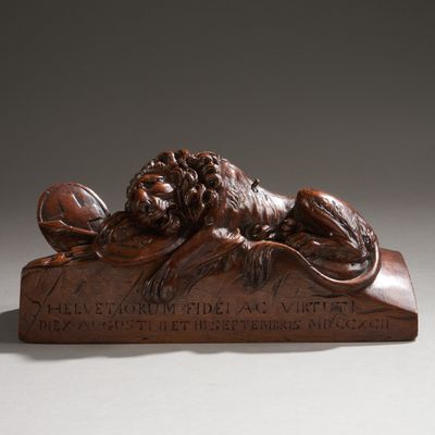 statue en bronze représentant un lion posé sur une plaque, tenant une boule entre ses pattes