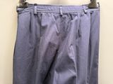 un pantalon violet suspendu à un cintre devant un mur blanc