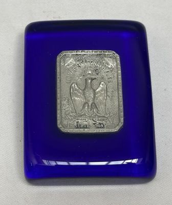 une image représentant une boîte en verre bleu ornée d'un sceau argenté
