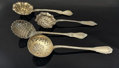 quatre cuillères en argent et des cuillères-cuillères posées sur un fond noir