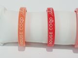 three different colored bracelets sitting on top of a white pillow
