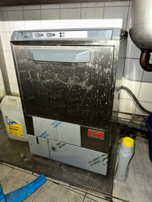 a dirty dishwasher in a dirty kitchen next to a trash can