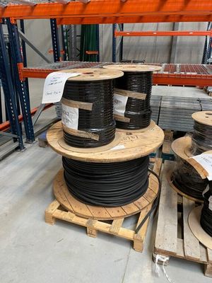 de nombreux rouleaux de fils noirs sur une palette dans un entrepôt