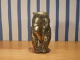 a gold owl figurine sitting on a wooden table