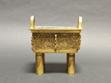 an image of a small brass incense box on a grey background