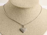 collier avec un cœur en argent, accroché à une chaîne autour du cou d'un mannequin