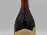 une vieille bouteille de vin rouge posée sur une table blanche