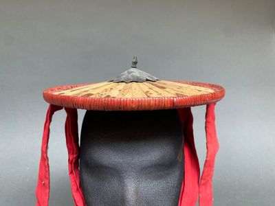 un chapeau posé sur la tête d'un mannequin, entouré d'une écharpe rouge
