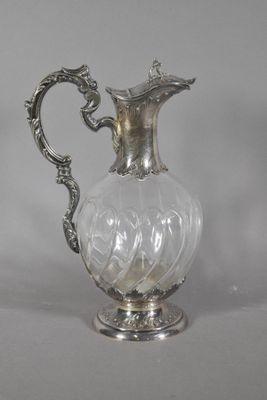 a silver and glass pitcher with a handle on a table