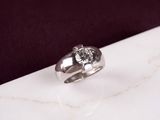 une bague en argent sertie d'un diamant, posée sur une surface en marbre