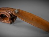 an old wooden pipe with a leather handle on a gray surface