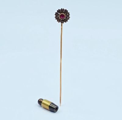 un petit bâton sur lequel est posée une fleur, à côté d'une balle