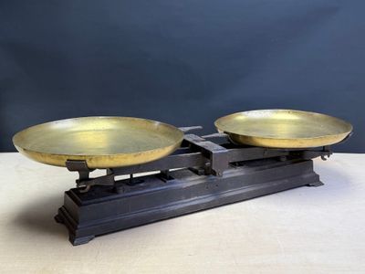 an antique brass scale with two bowls on top of it