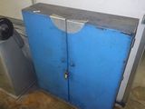 a blue cabinet in a garage with a water heater in the corner