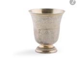 une coupe ancienne en argent posée sur un socle, sur fond blanc