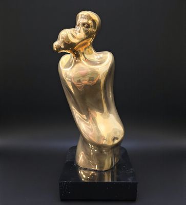 une sculpture en or représentant une femme tenant un bébé dans ses bras, posée sur un socle noir