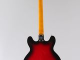 an electric guitar hanging from a string on a white wall