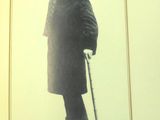 une photo en noir et blanc d'un homme portant un haut-de-forme et un manteau, muni d'une canne