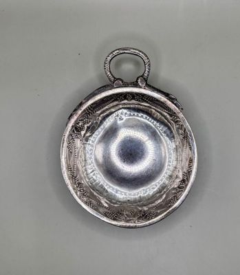 an old silver plate with a circular design hanging from it ' s side