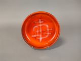 an orange bowl with a bitcoin on it sitting on a table