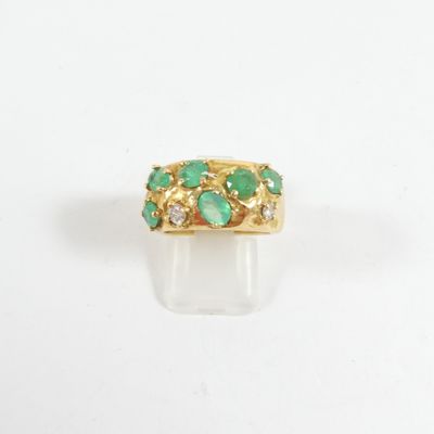 Gros plan sur une bague en or ornée d'émeraudes et de diamants