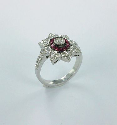 gros plan d'une bague en diamant et rubis sur une surface blanche