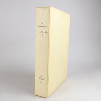 un vieux livre posé sur une table à côté d'un mur blanc