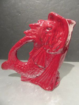 a red vase with a fish on it sitting on a table