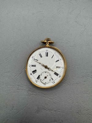 a gold clock with roman numerals hanging on the wall