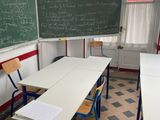 tables and chairs in a classroom with a blackboard and a chalkboard