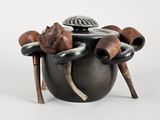 un pot noir muni de poignées en bois et surmonté d'un chapeau