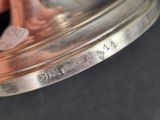 a person holding a silver bell on a black surface