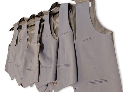 five suits hanging on a clothes rack on a white wall